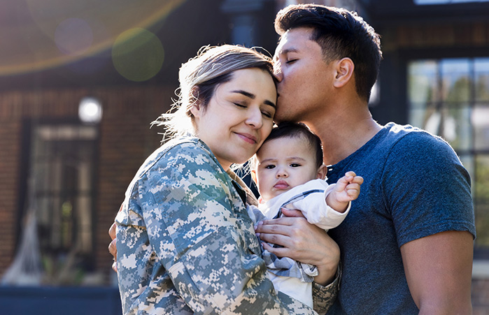 Husband kissing his wife holding their child.