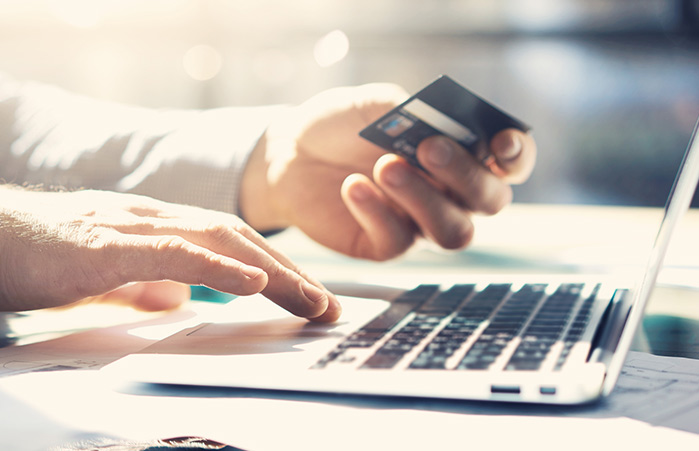 Person holding a credit card using a laptop.