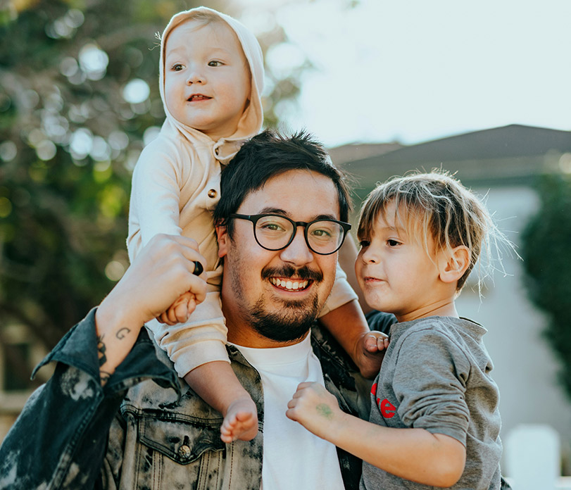 Father holding his children outdoors.