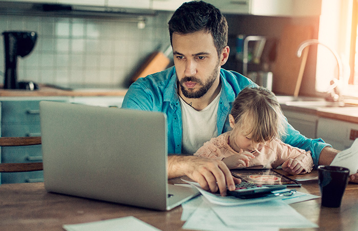 Person holding their child working on their laptop.
